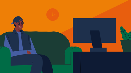 Een jongeman met bril en pet achterstevoren zit op een groene bank en kijkt met enthousiaste blik naar de televisie