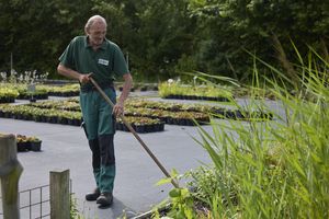Een man in groen uniform is aan het schoffelen.