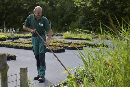 Een man in groen uniform is aan het schoffelen.