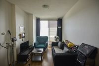 Woonkamer met een bank, een stoel en een televisie.