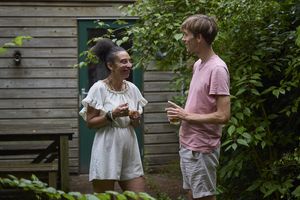 Een bewoonster staan in de tuin met een begeleider, ze drinken een kopje thee.
