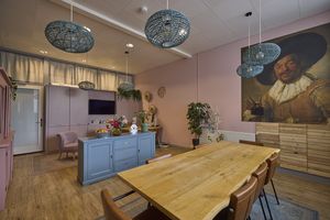 Woonkamer met eettafel en zithoek, er hangt een Rembrandt schilderij aan de muur.