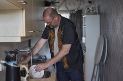 Een man doet de afwas in de keuken.
