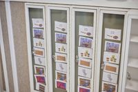Vier vitrines met glazen deuren met afbeeldingen en teksten die dagplanningen weergeven.