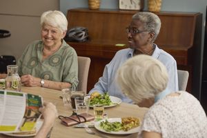 Drie bewoonsters zitten aan tafel en nuttigen een warme maaltijd.