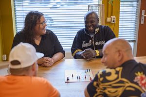 Vier mensen zitten aan tafel en spelen het bord spel mens erger je niet.