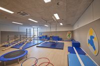 Een kinderspeelzaal met klimrekken, hellingen, een trampoline en schuimmatten.