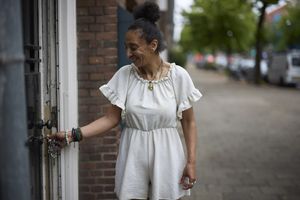 Een vrouw doet de voordeur van haar woning open.