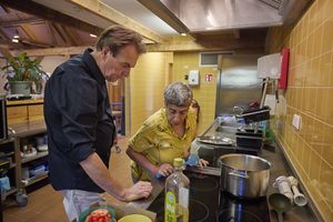Man en vrouw staan in de keuken bij het fornuis en gaan een maaltijd bereiden