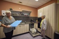 Twee vrouwen ruimten de vaatwasmachine uit, de ene droogt een blauw dienblad af.