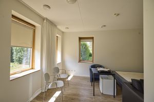 Een slaapkamer met witte muren een bed en een aantal stoelen.