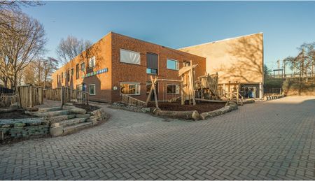 Gebouw Speciaal Onderwijs Van Koetsveldschool. Zorgonderwijsgroep. Schoolplein met houten speeltoestellen.