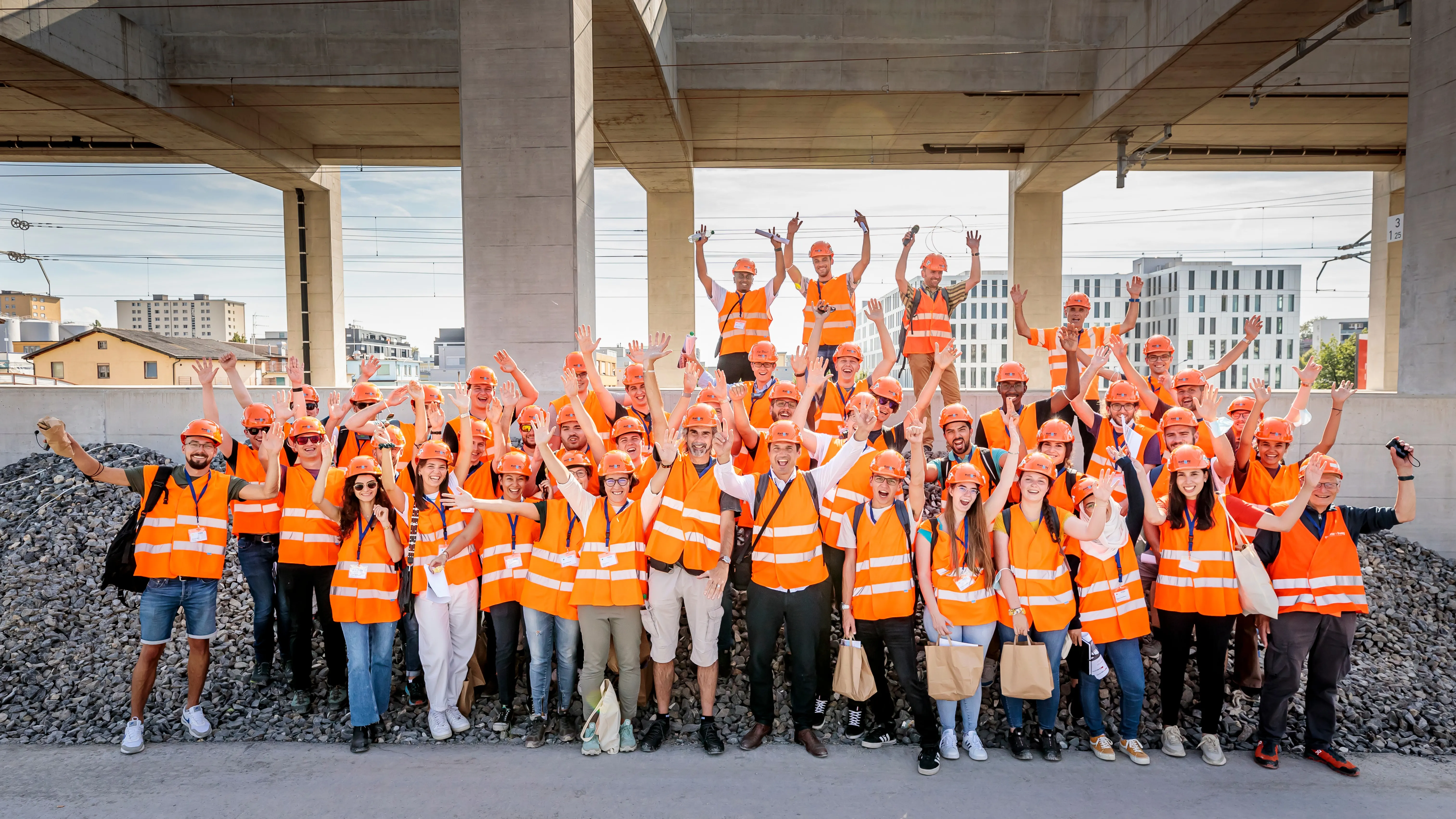 Des personnes portant casques de protection et gilets orange lèvent les mains.