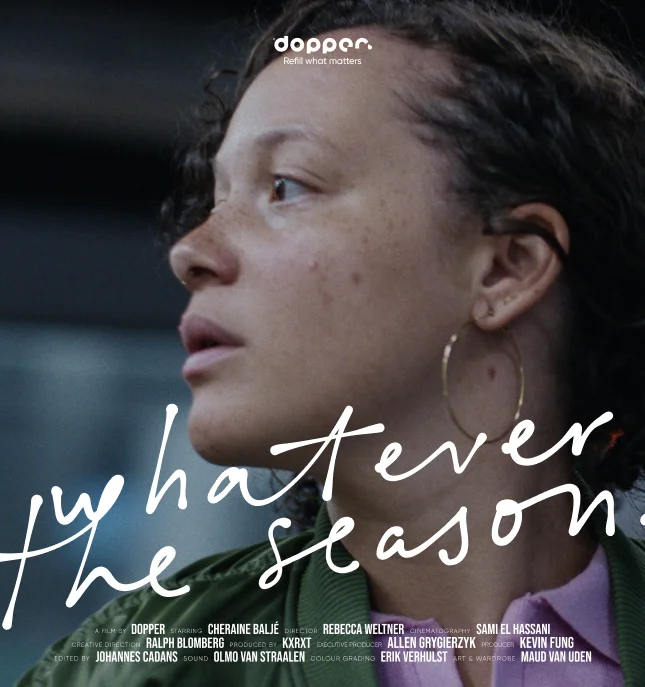 A woman with curly hair and freckles looks to the side. Text reads "whatever the season" with names listed below. A Dopper movie.