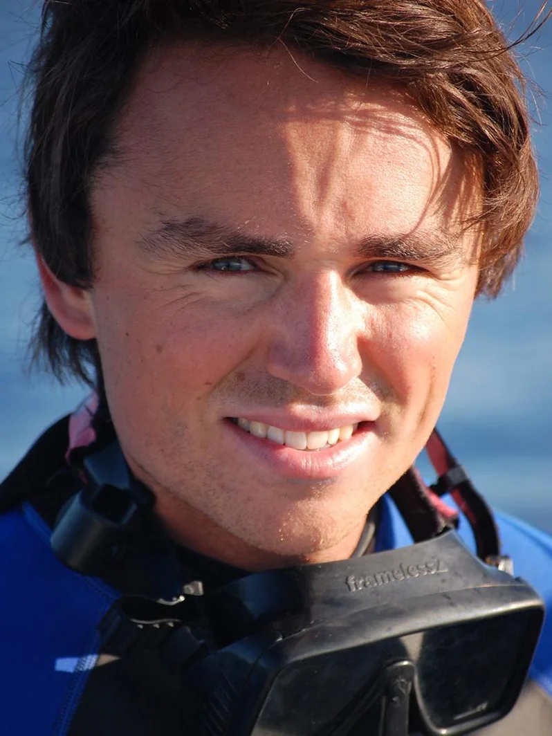 Smiling man wearing scuba gear and goggles around his neck