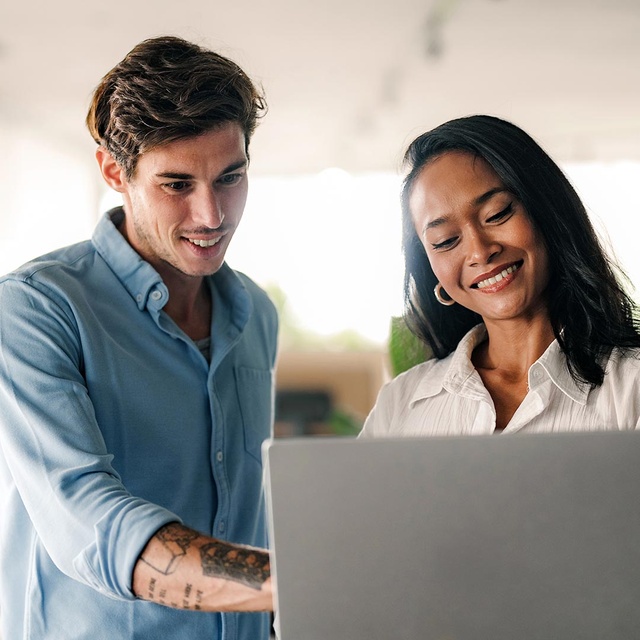 Zwei Kollegen sehen sich im Büro gemeinsam etwas auf einem Laptop-Bildschirm an. Sie besprechen eine Integration der websms RCS API in ihre Kommunikationsprozesse.