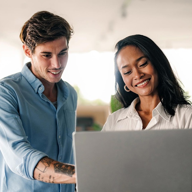 Zwei Kollegen sehen sich im Büro gemeinsam etwas auf einem Laptop-Bildschirm an. Sie besprechen eine Integration der websms RCS API in ihre Kommunikationsprozesse.