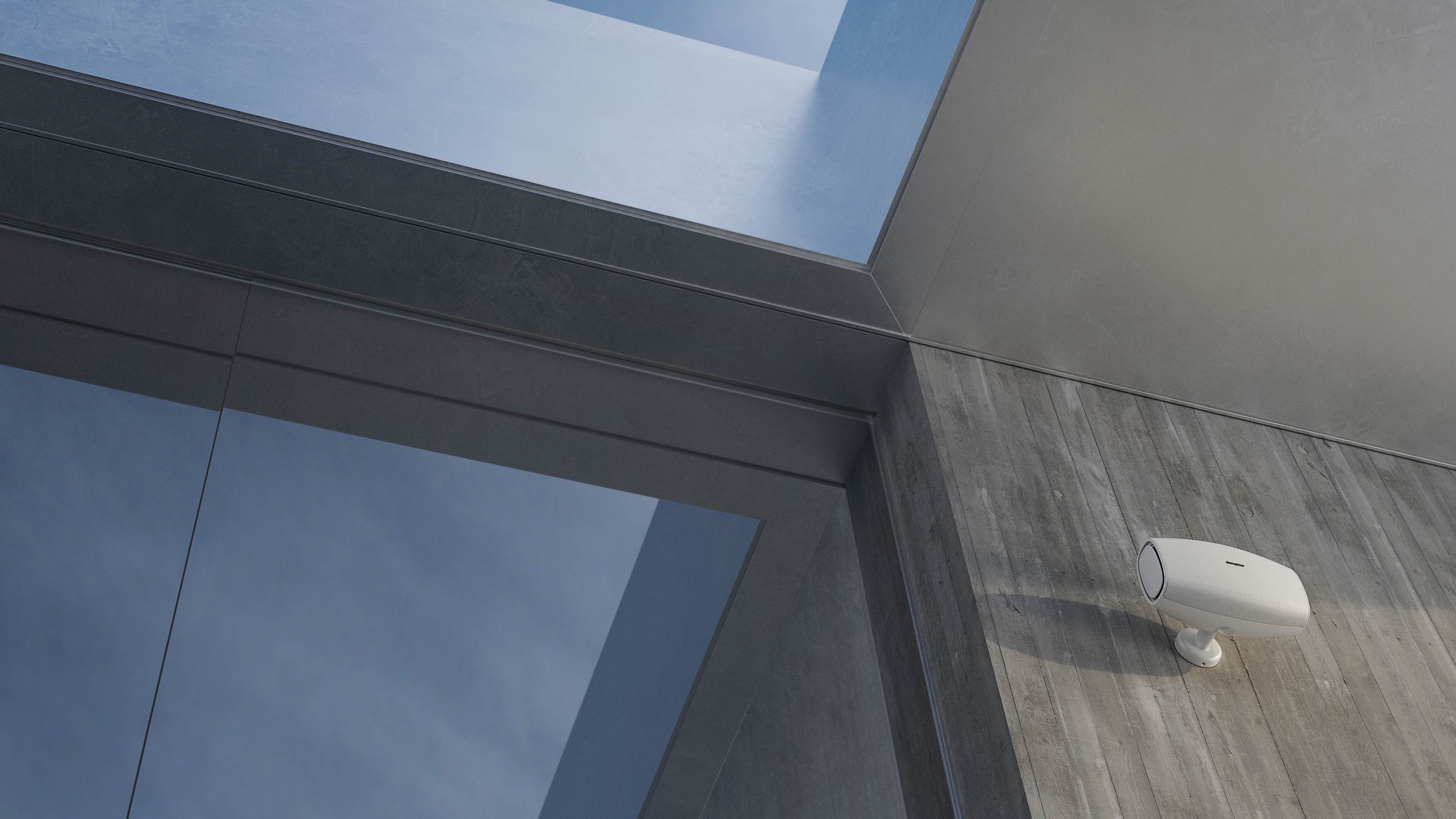 Sonus faber outdoor speaker in white, mounted on an exterior cement wall, displaying its sleek design.