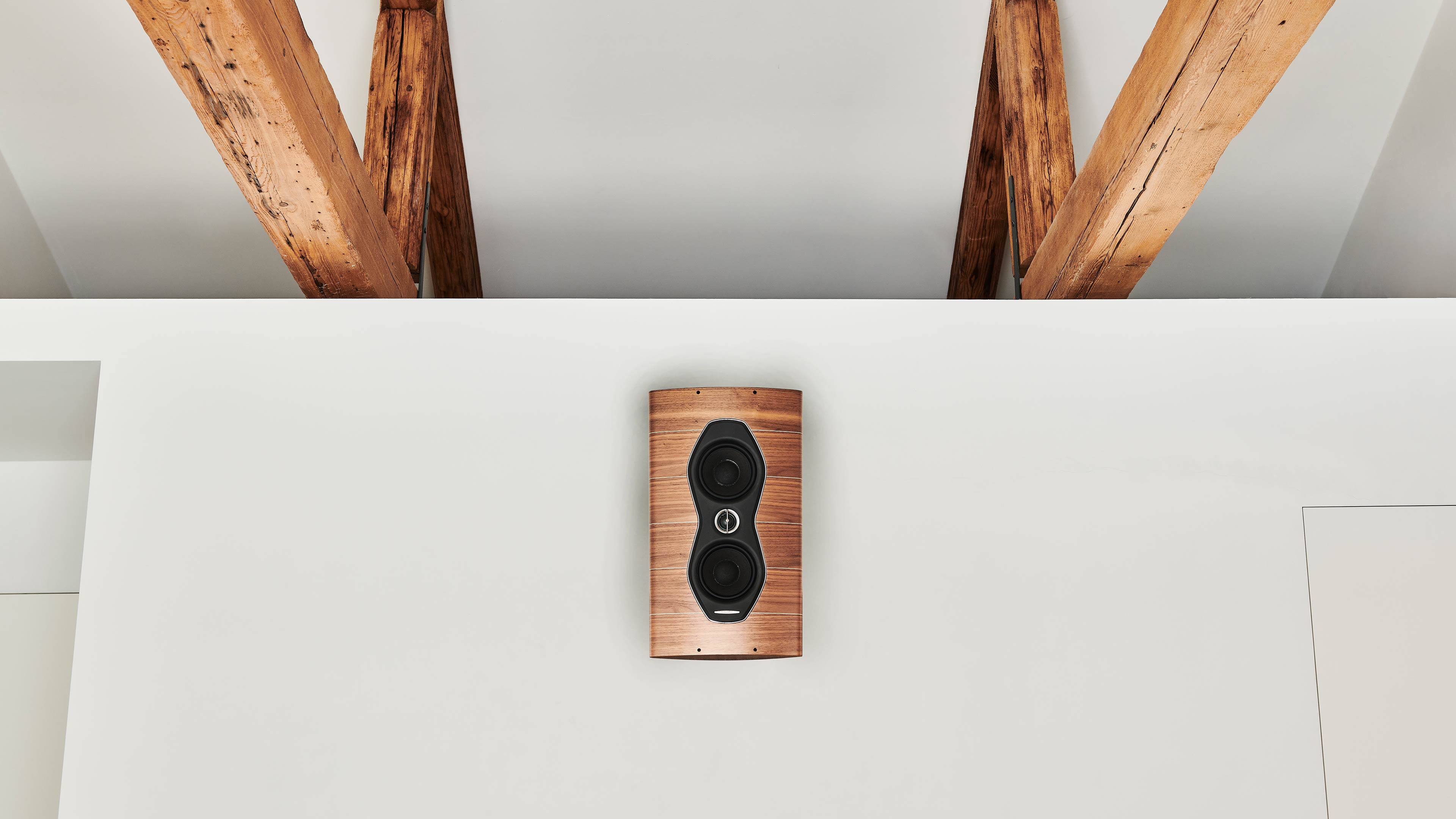 Sonus faber Olympica Nova W on-wall speaker elegantly adorning a home wall, complementing the overhead wood beams.