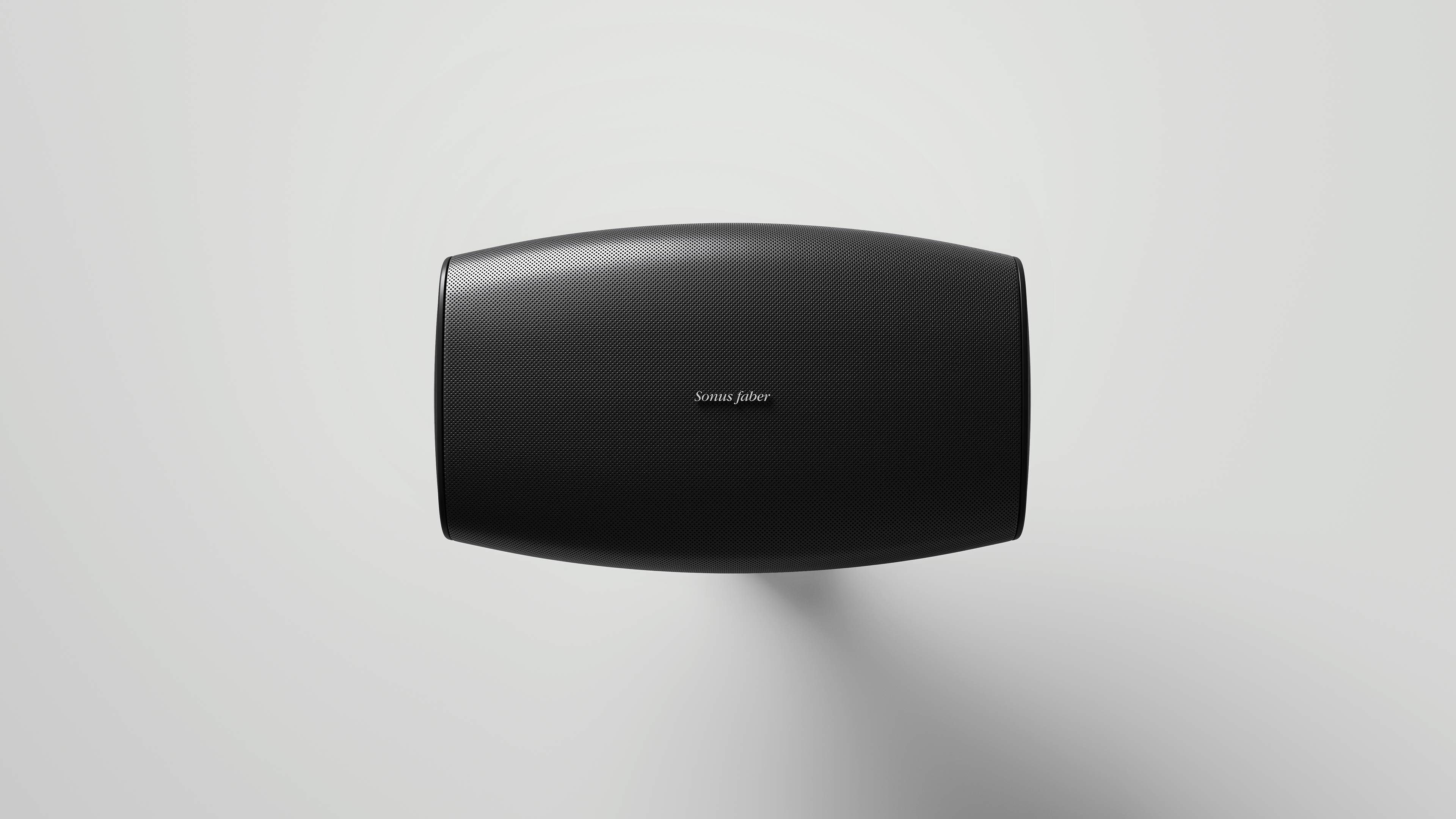 Sonus faber Aster outdoor speaker in black on a white wall, showcasing contrasting colors and a clean, modern design.