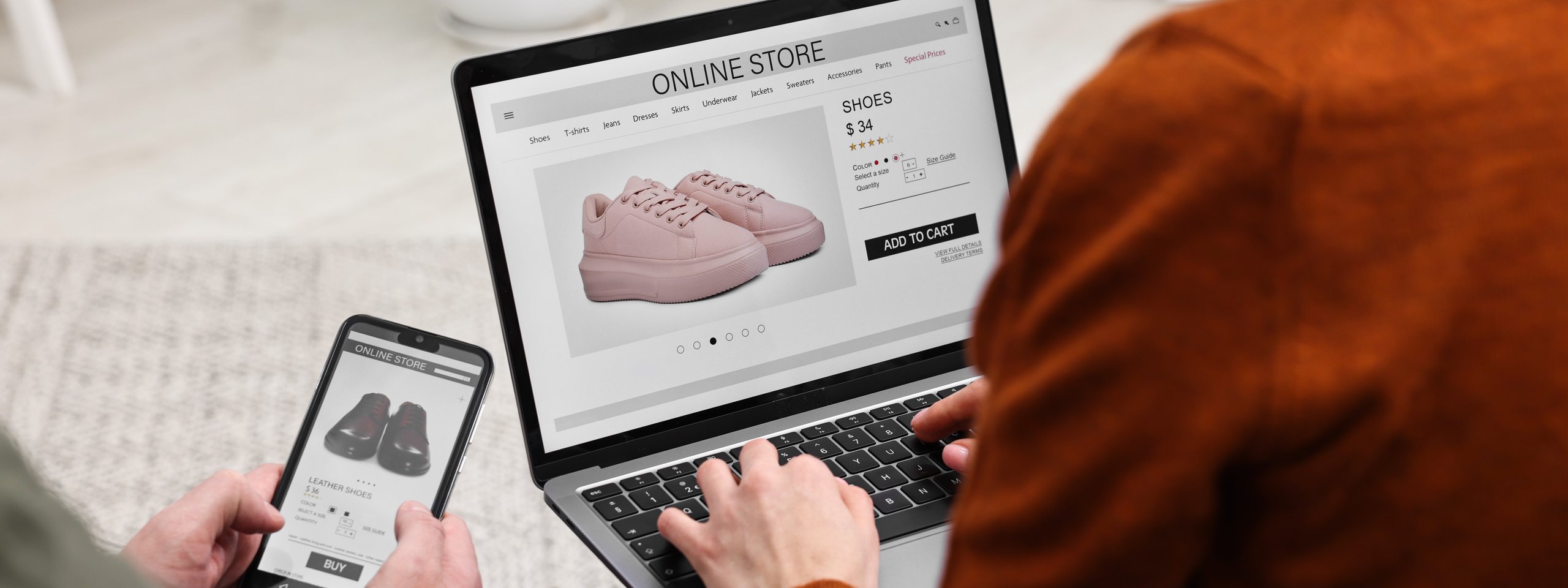 Two people shopping online for shoes, using a laptop and a smartphone. Pink sneakers displayed on the laptop screen.
