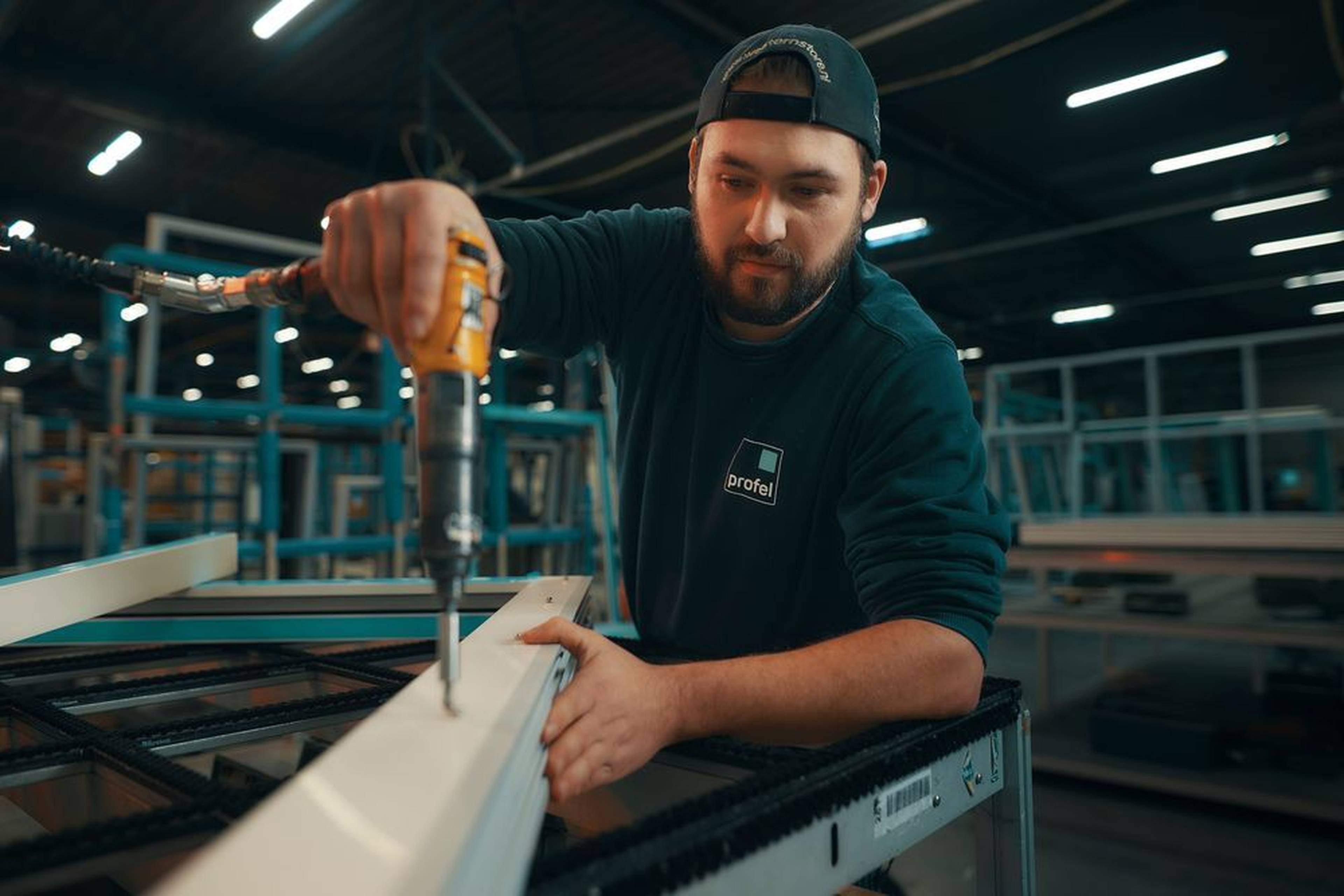 Membre du personnel de Profel Group au travail dans le hall de production PVC à Pelt, Belgique