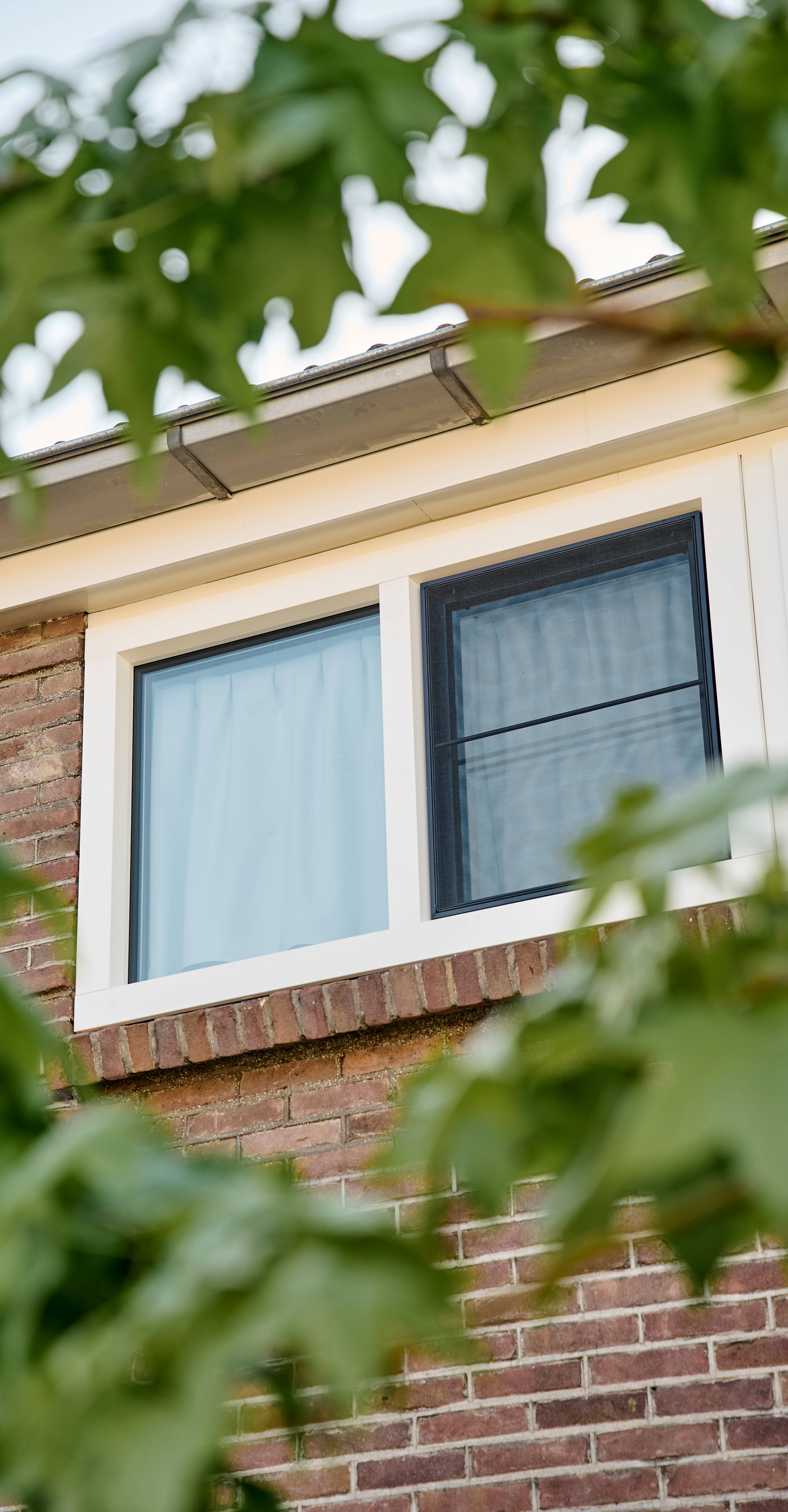 Klassieke woning met witte kunststof blokramen met bijpassende hor
