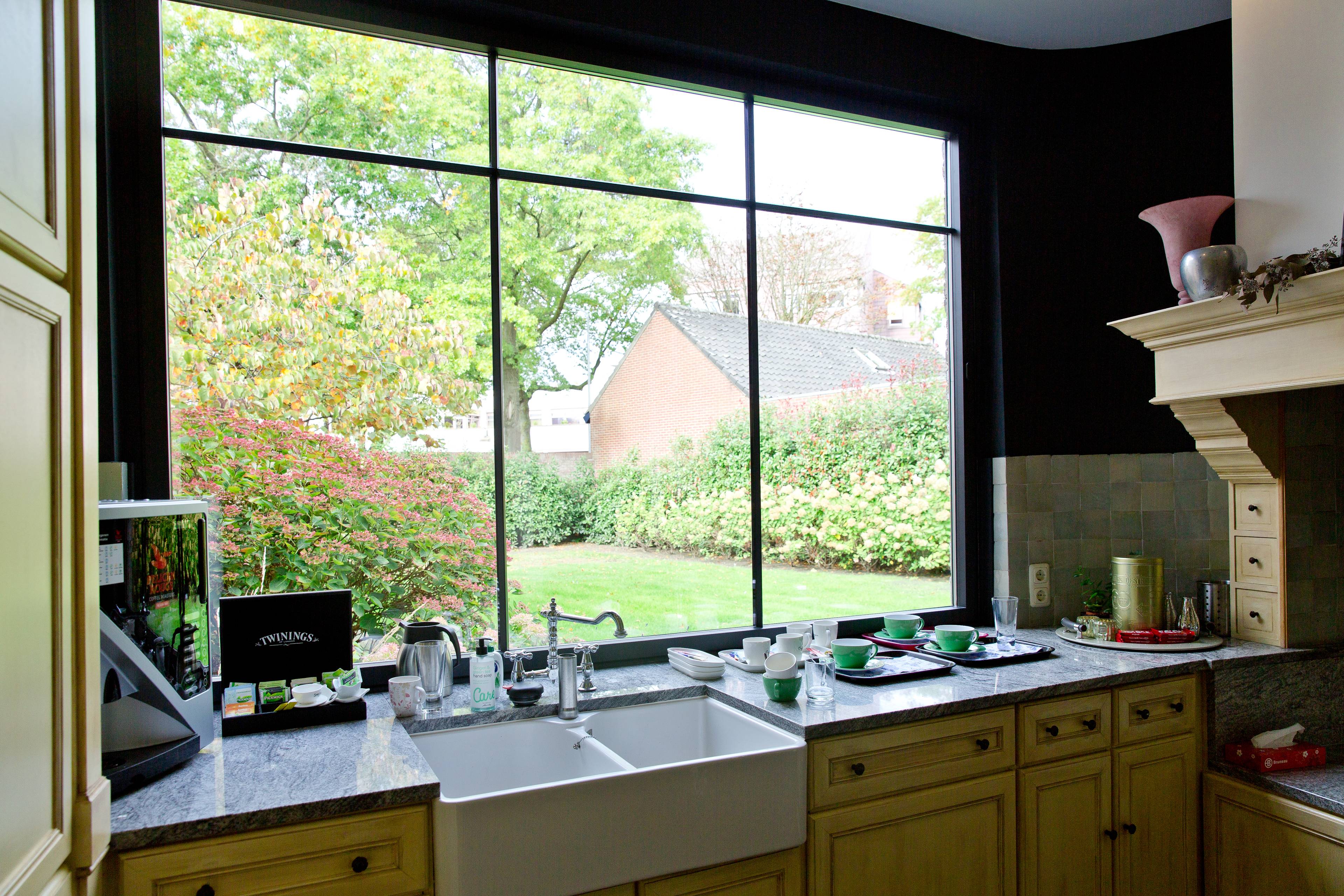 Vue intérieure d’une cuisine rurale avec des châssis en aluminium noirs épurés à croisillons de Profel.