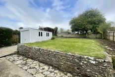 Garden with a wall up to grass area, small patio area and a garage on the left