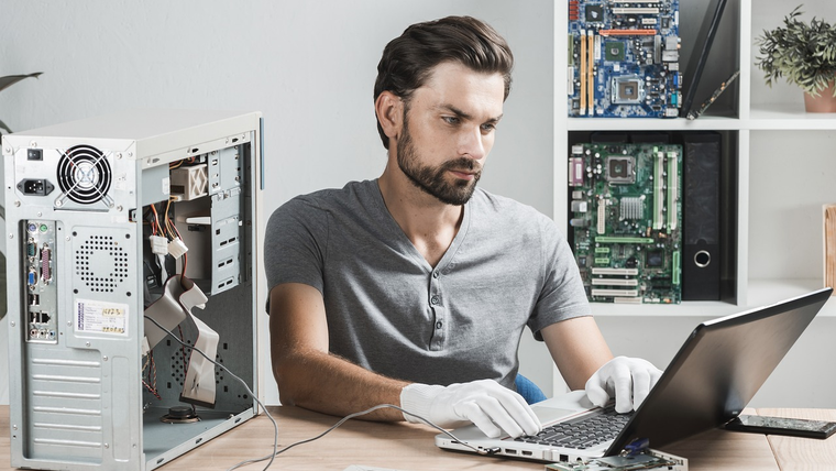 Technician repairing a computer and checking data on a laptop