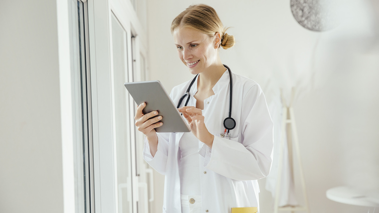 Doctor holding a tablet and smiling.