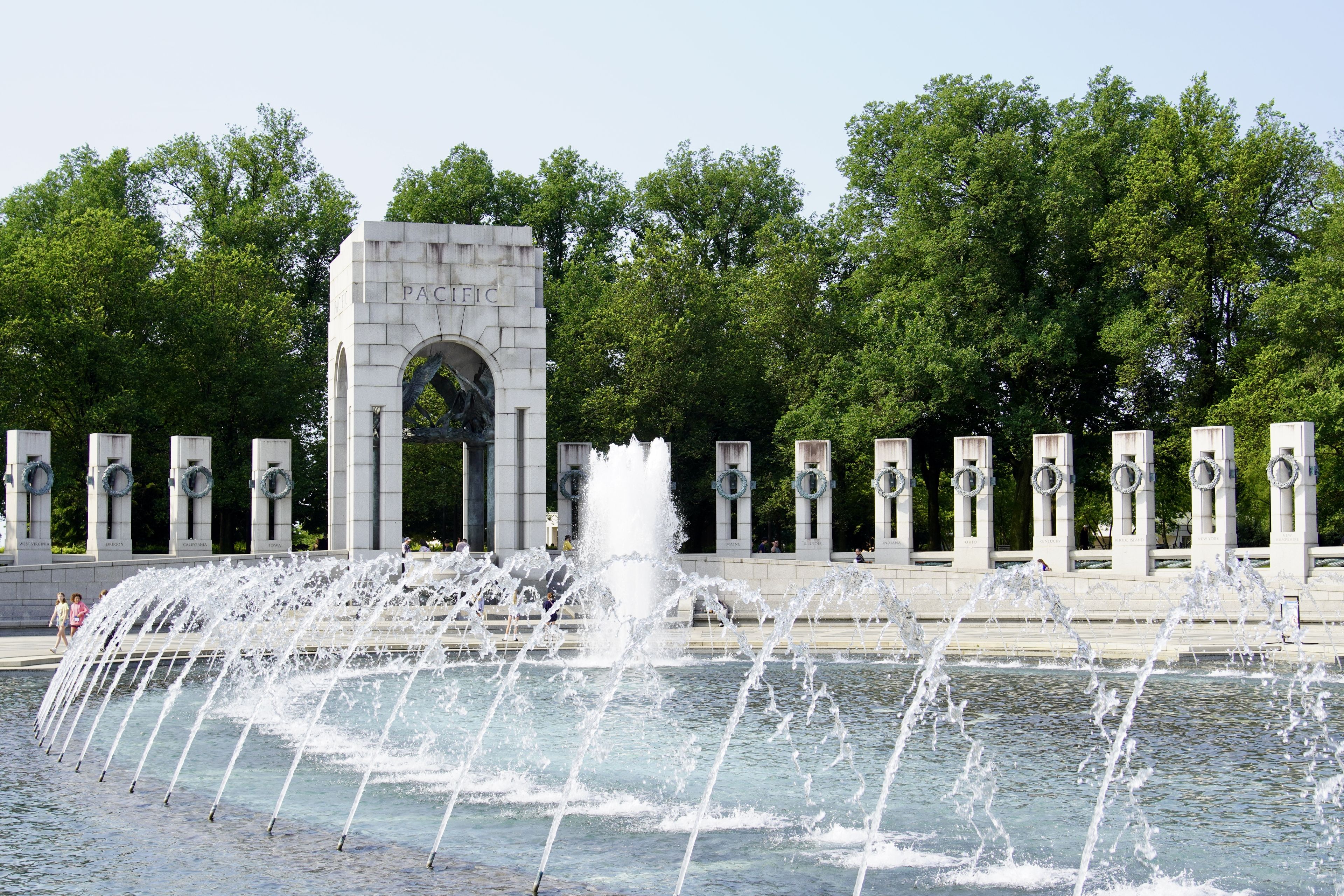 Fountain at the World War II Memorial in Washington, D.C., with the Pacific arch and wreath-adorned pillars in the background.