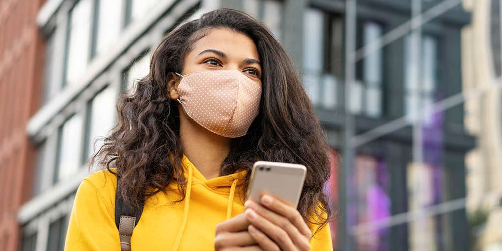 Student outside with a face mask on her phone