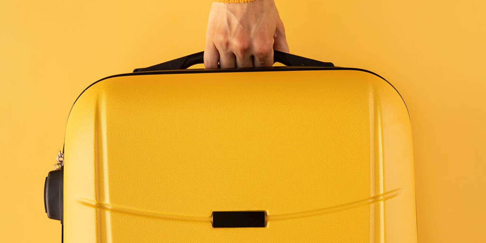 Woman holding yellow suitcase on a yellow background