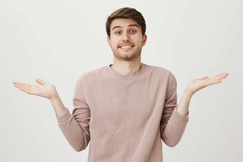 Young male student shrugging shoulders