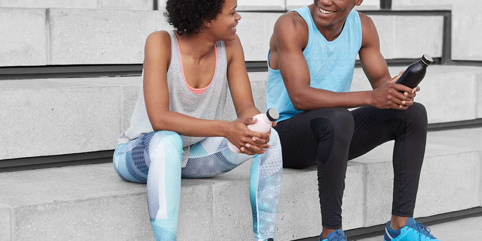 Two young people, man and woman relaxing outside after working out