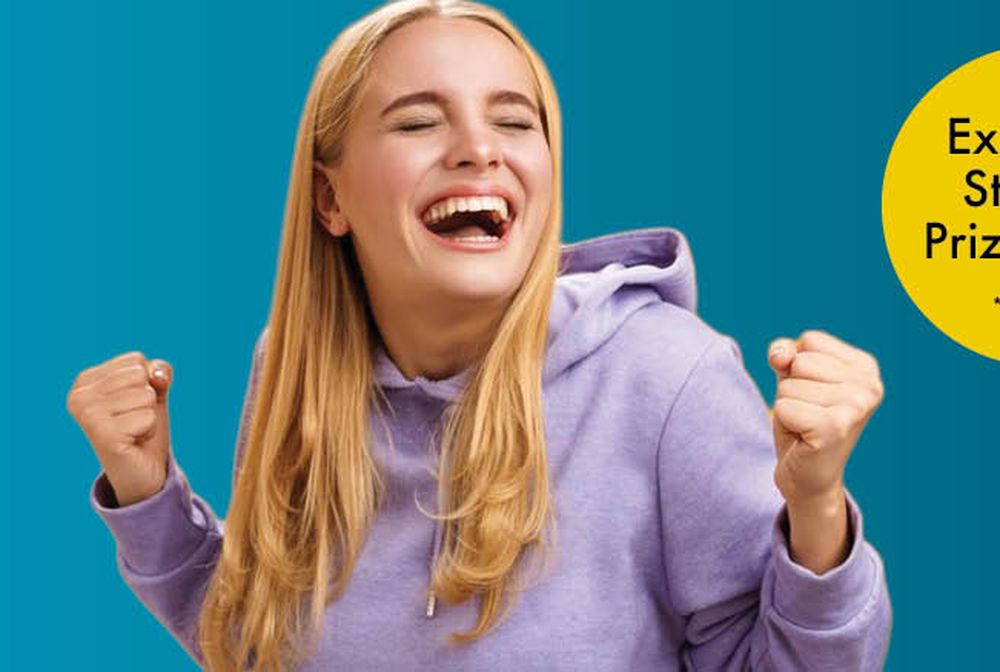 Smiling person in a purple hoodie celebrates with fists raised. Yellow circle reads, "Exclusive Student Prize Draw *T&Cs apply." Blue background.