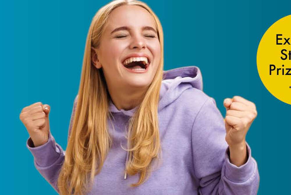 Smiling person in a purple hoodie celebrates with fists raised. Yellow circle reads, "Exclusive Student Prize Draw *T&Cs apply." Blue background.