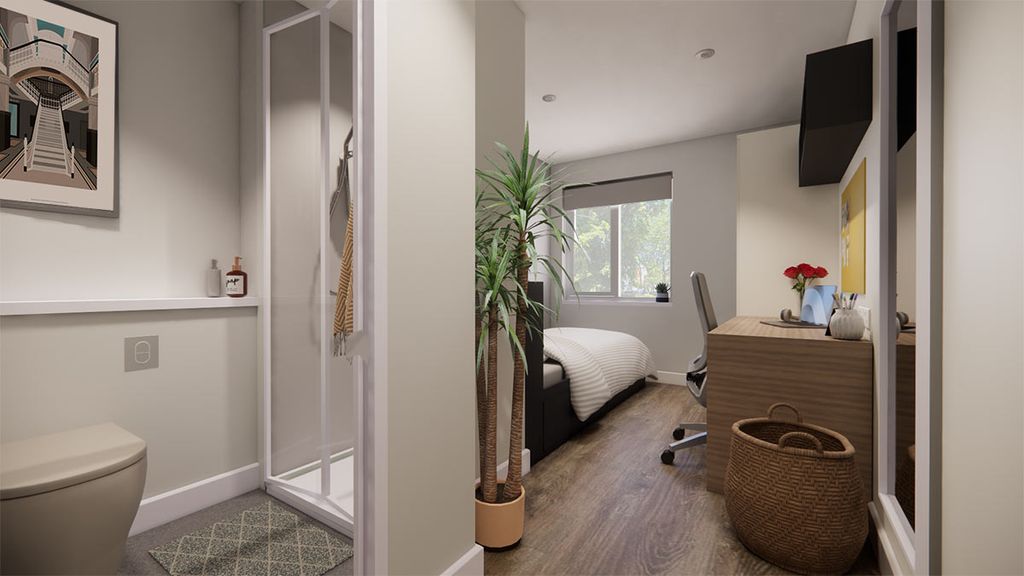 Compact modern studio: bathroom with shower and toilet opens into bedroom with a bed by the window, desk, chair, plant.