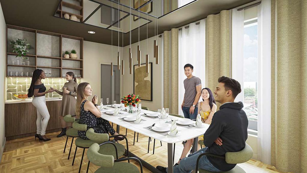 Six people chatting around a set dining table in a modern, sunlit apartment dining area with the kitchen visible in the background.