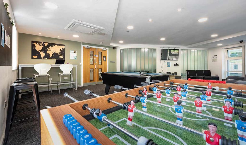Recreation room with foosball table, pool table, bar stools, map wall art, and a wall-mounted TV. Cozy, modern, and inviting space.