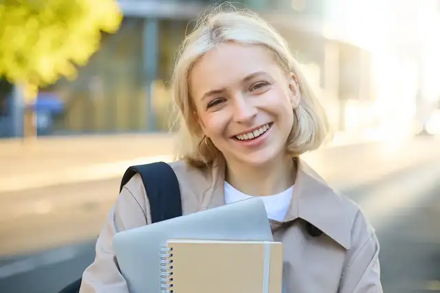 Close up image of smiling student with laptop and notepad