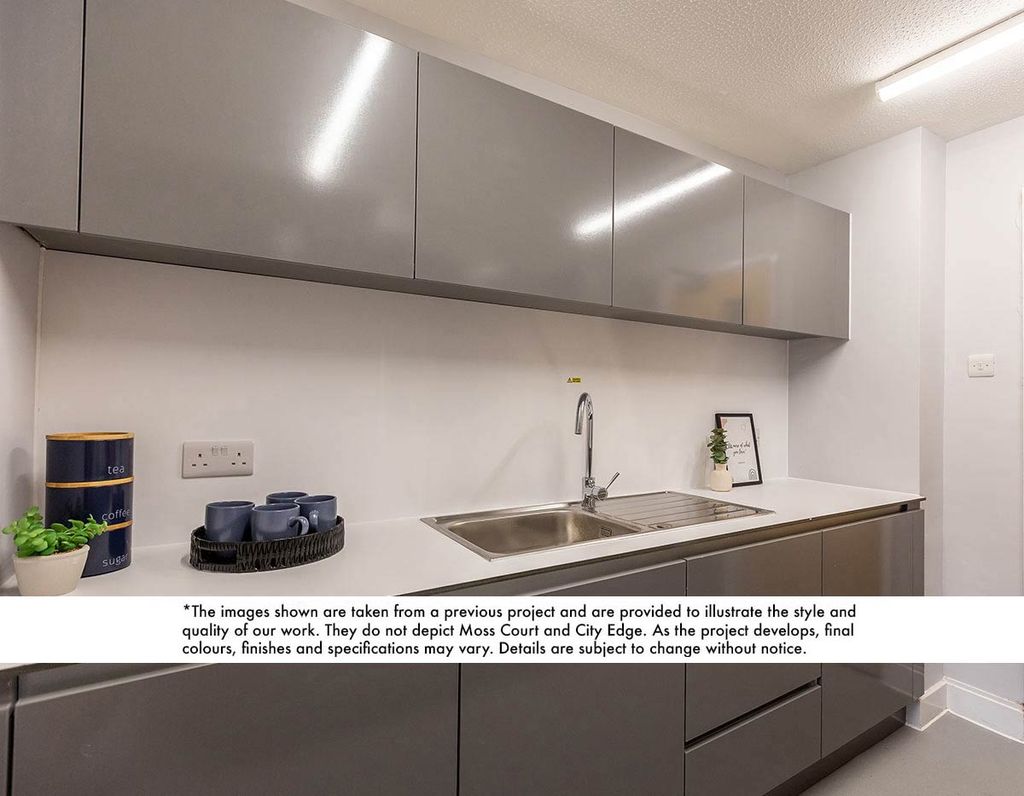 Modern kitchen with glossy gray cabinets, a stainless steel sink, blue canisters, and cups on a white countertop.