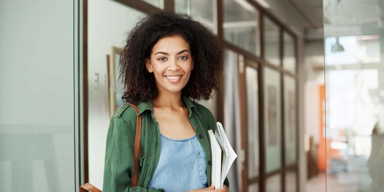 Woman student standing in a corridor holding books and notes