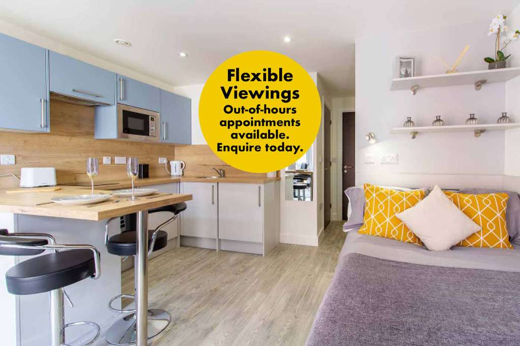 Modern studio apartment with kitchenette, bar stools, bed, and colorful cushions. Yellow text reads: "Flexible Viewings. Out-of-hours appointments available. Enquire today."