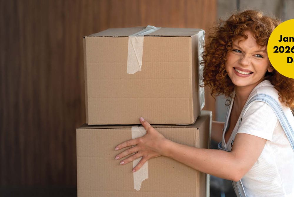 Smiling woman with curly hair holding two cardboard boxes, wearing overalls. Yellow circle reads "January 2026 Start Date."