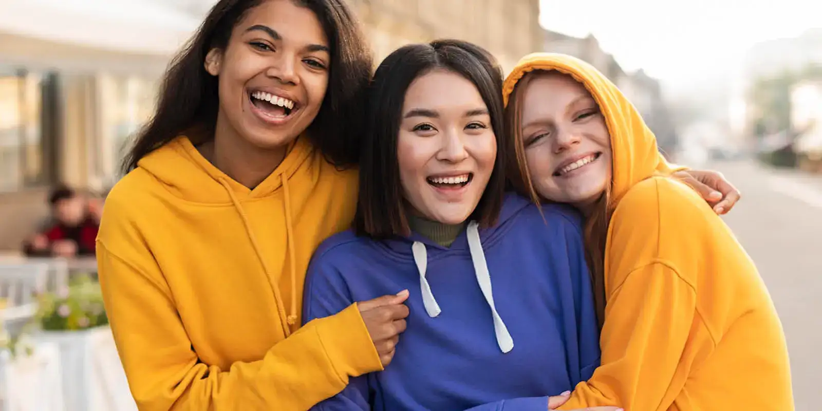 Three friends hugging each other smiling