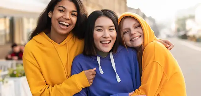 Three friends hugging each other smiling