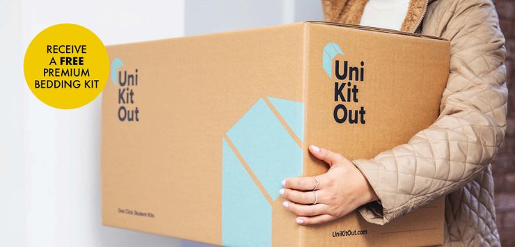 Person carrying a large Uni Kit Out box with a yellow sticker offering a free premium bedding kit.