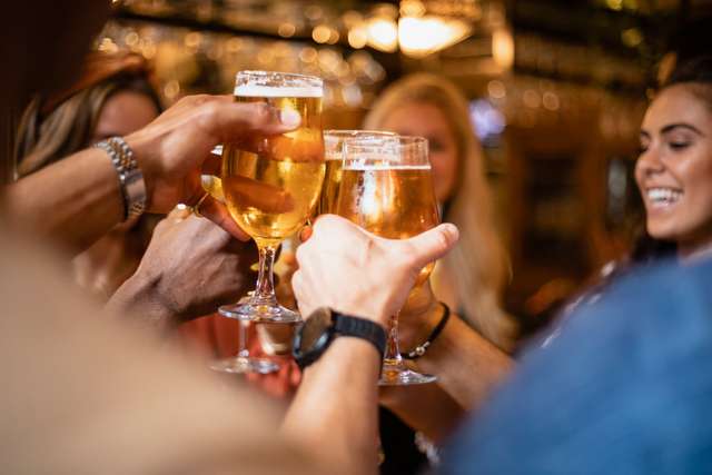 Group of students toasting pints of lager